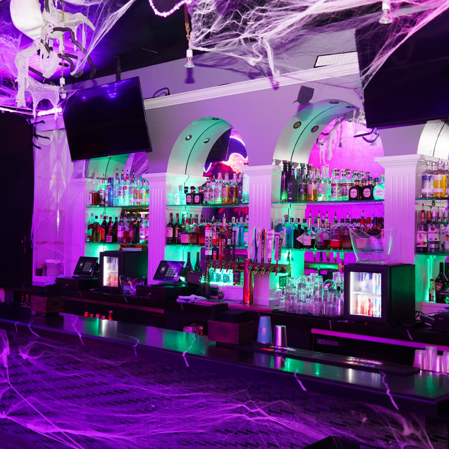 Stylish bar interior with green lights, modern tiles, and sleek shelves reflecting luxury design.