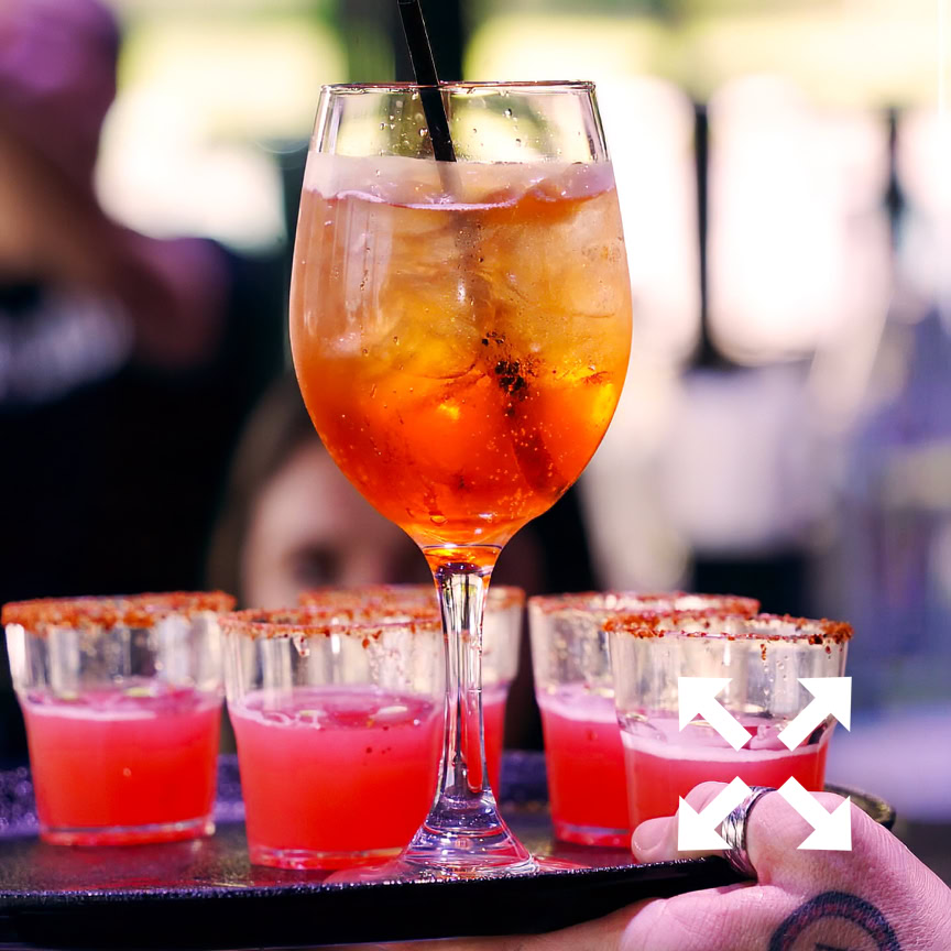 A stylish green cocktail in a glass sits on a dimly lit bar table, creating a moody atmosphere.